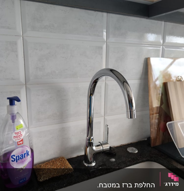 ברז מטבח נירוסטה על רקע קיר אריחים לבנים